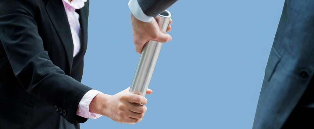 Eine Businessfrau übergibt einen Staffelstab an einen Businessmann als Symbol für Terminverschiebungen im ISO-20022-Zeitplan.