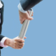 Eine Businessfrau übergibt einen Staffelstab an einen Businessmann als Symbol für Terminverschiebungen im ISO-20022-Zeitplan.
